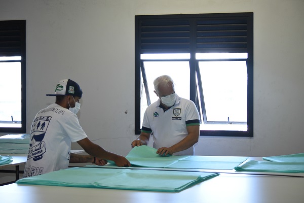 #PraCegoVer: Fotografia do interior da fábrica de máscaras. Na imagem, profissionais trabalhando 